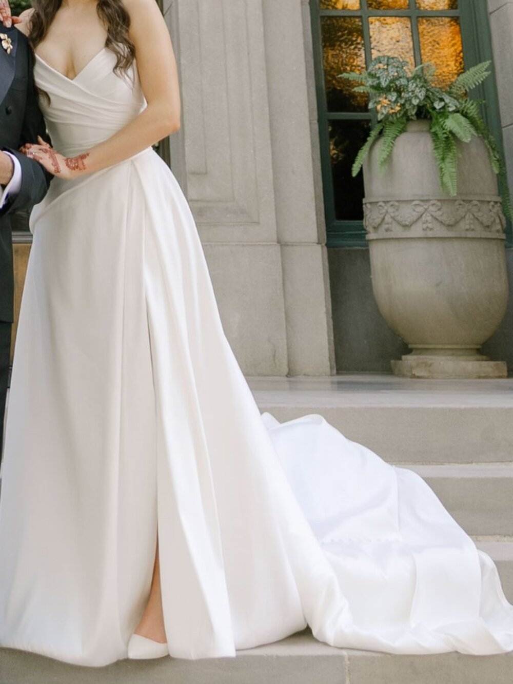 Strapless white wedding dress with asymmetrical waistline, high slit, and train